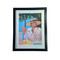 Framed art print of a woman wearing a hat sitting a a table
